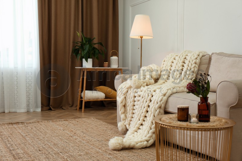 Soft knitted blanket on couch in living room. Interior element