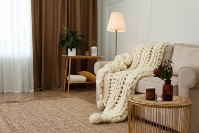 Soft knitted blanket on couch in living room. Interior element