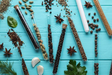 Flat lay composition with various spices, test tubes and fresh herbs on light blue wooden background
