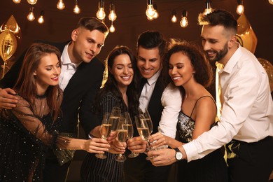 Photo of Happy friends with glasses of sparkling wine celebrating New Year indoors
