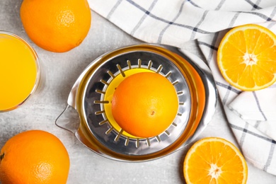 Fresh ripe oranges, juice and squeezer on grey table, flat lay