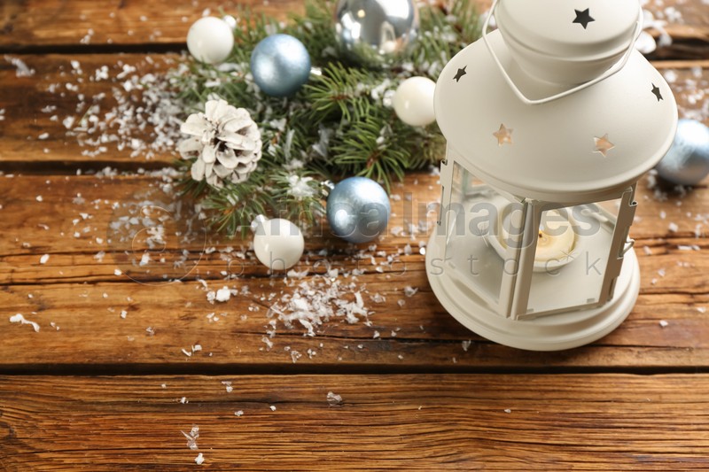 Photo of Christmas lantern with burning candle and festive decor on wooden table