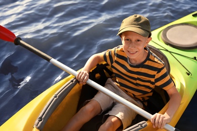 Happy little boy kayaking on river, above view. Summer camp activity