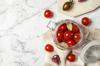 Pickling jar with fresh ripe cherry tomatoes on white marble table, flat lay. Space for text