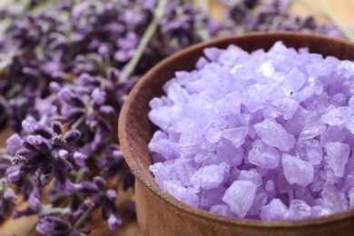 Wooden bowl of natural lavender bath salt and flowers on table, closeup with space for text. Cosmetic product