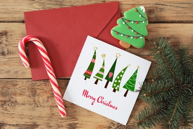 Greeting card with text Merry Christmas on wooden table, flat lay