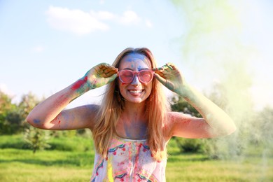 Happy woman covered with colorful powder dyes outdoors. Holi festival celebration
