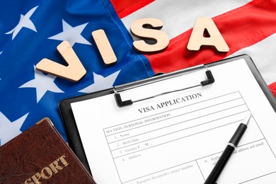 Word Visa, application form and passport on American flag. Immigration to USA