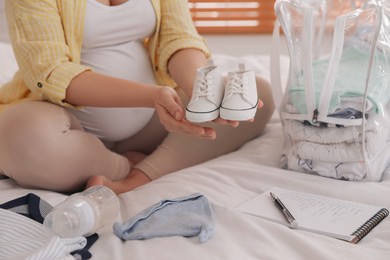Pregnant woman packing bag for maternity hospital at home, closeup