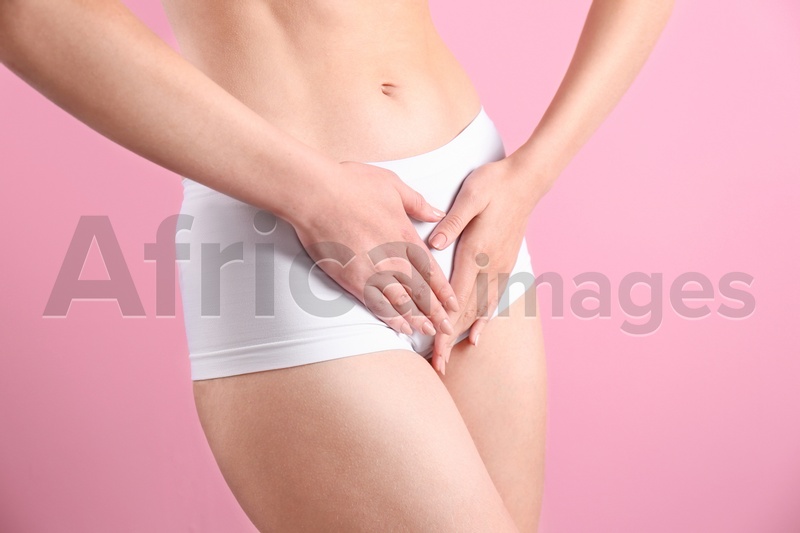Young woman holding hands near underwear on color background. Gynecology