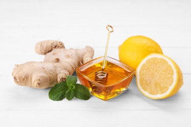 Photo of Natural cough remedies. Bowl with honey, ginger, mint and lemon on white table