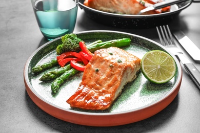 Plate with tasty cooked salmon on table, closeup