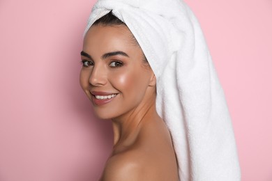 Beautiful young woman with towel on head against pink background
