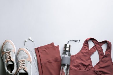 Flat lay composition with sportswear and equipment on light grey background, space for text. Gym workout