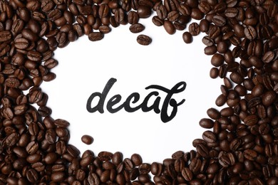 Word Decaf and coffee beans on white background, top view