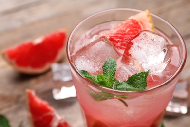 Glass of refreshing drink with grapefruit and mint on wooden table, closeup view. Space for text