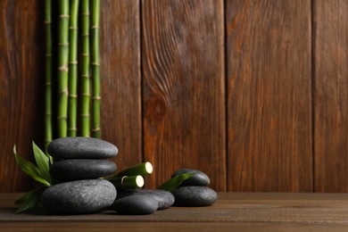 Spa stones and bamboo stems on wooden table. Space for text