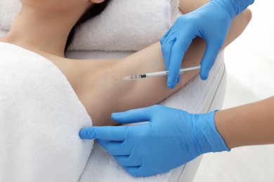 Cosmetologist injecting young woman's armpit in clinic, closeup. Treatment of hyperhidrosis