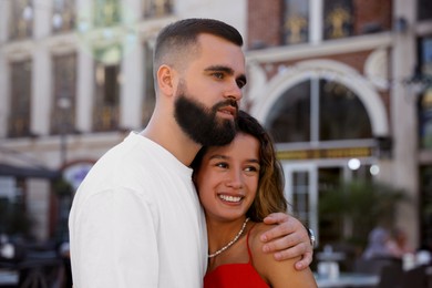 Happy young couple hugging on city street