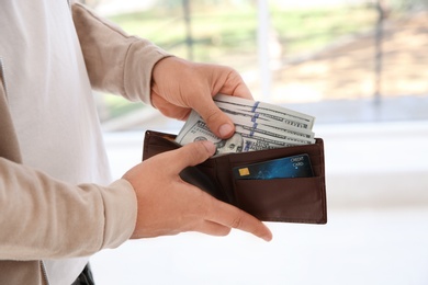 Man holding wallet with money on blurred background, closeup