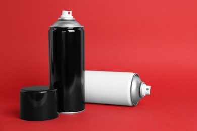 Photo of Cans of spray paints on red background