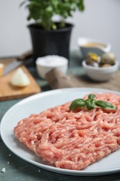 Raw chicken minced meat with basil on light blue table, closeup