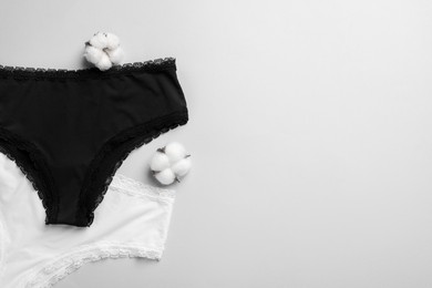 Photo of Women's underwear and cotton flowers on light grey background, flat lay. Space for text
