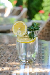 Photo of Refreshing water with lemon and mint on glass table in cafe