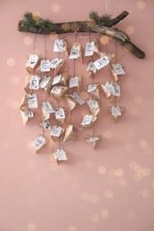 Photo of Christmas advent calendar with small gifts hanging on pink wall