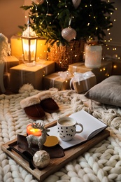 Wooden tray with cocoa, candle and notebook in room decorated for Christmas