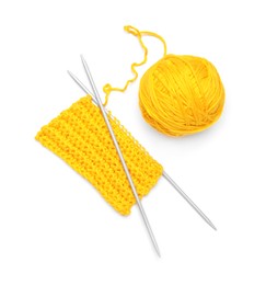 Soft yellow woolen yarn, knitting and metal needles on white background, top view