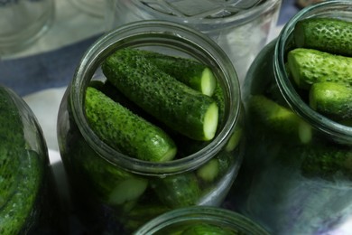 Glass jars with fresh ripe cucumbers on table, closeup. Pickling vegetables
