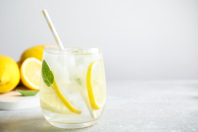 Glass of cold lemonade on light grey table, closeup. Space for text