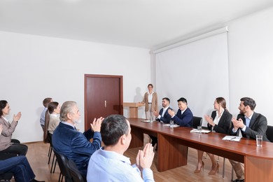 Photo of People applauding to speaker at business conference in meeting room