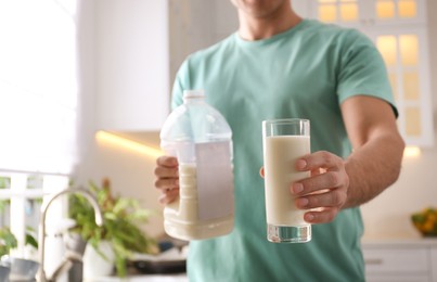 Man with gallon bottle of milk and glass in kitchen, closeup