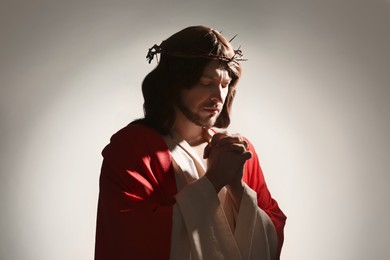 Jesus Christ with crown of thorns praying on white background