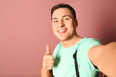 Young handsome man taking selfie against color background