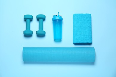 Exercise mat, dumbbells, towel and shaker on light blue background, flat lay