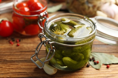 Glass jar of pickled cucumbers on wooden table, closeup