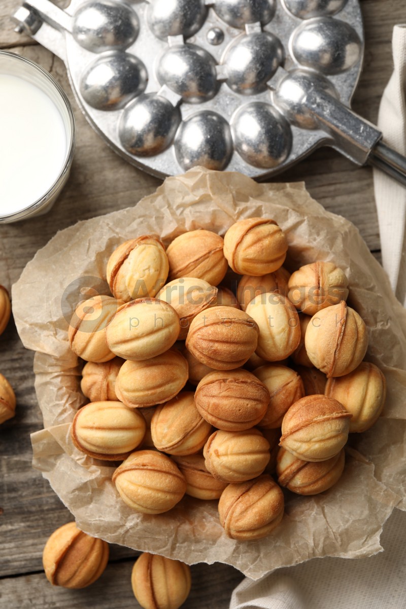 Photo of Bowl of delicious nut shaped cookies on wooden table, flat lay