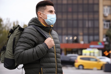 Male tourist with respiratory mask on city street. Travelling during COVID-19 pandemic
