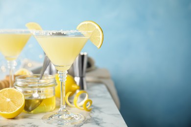 Delicious bee's knees cocktails and ingredients on white marble table against light blue background. Space for text