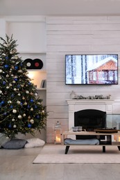 Stylish living room interior with modern TV, fireplace and Christmas tree