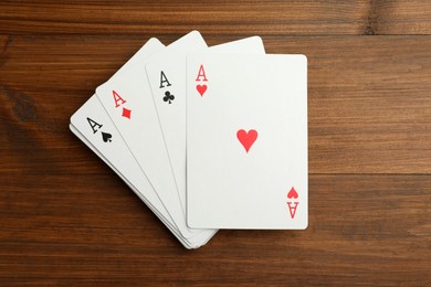 Four aces playing cards on wooden table, flat lay