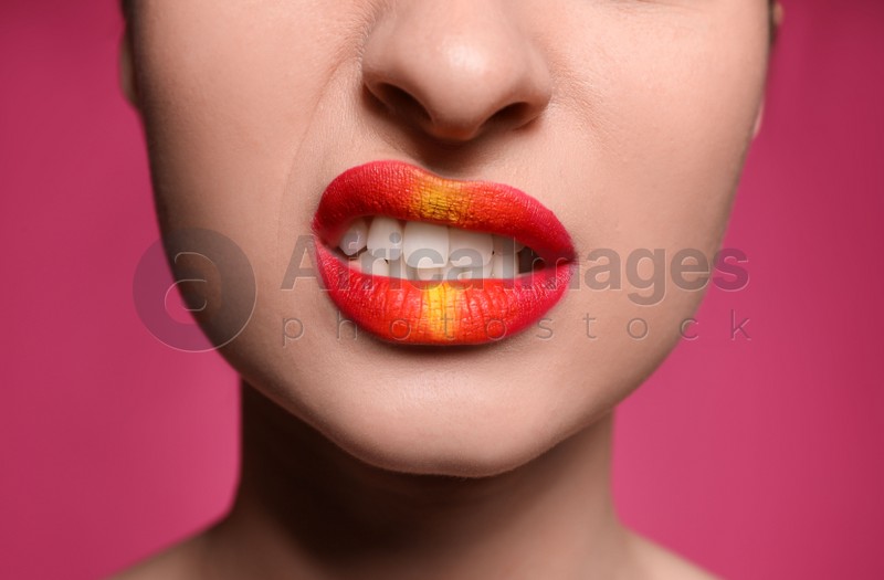 Young woman with beautiful lips makeup on pink background, closeup