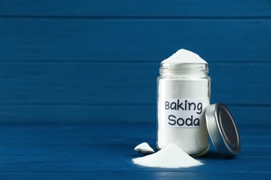 Jar and spoon with baking soda on blue wooden table. Space for text