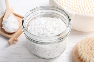 Sea salt for spa scrubbing procedure in jar on white wooden table