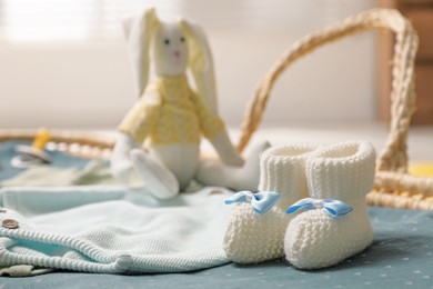 Baby booties and clothes in basket indoors, closeup. Space for text