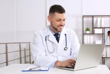 Pediatrician working on laptop at desk in office