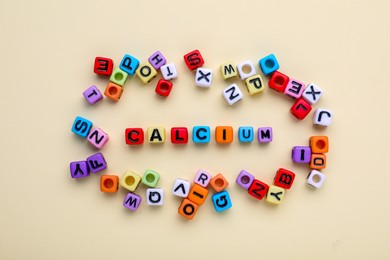 Word Calcium made of colorful plastic beads with letters on beige background, top view